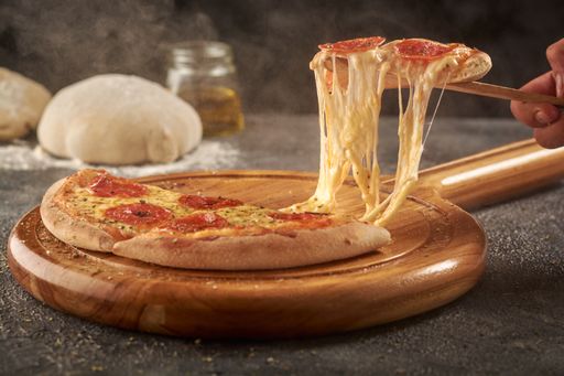 A hand grabbing a slice of delicious cheesy pepperoni pizza with a wooden spatula