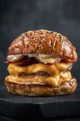 A vertical shot of a delicious double cheeseburger on a blackboard
