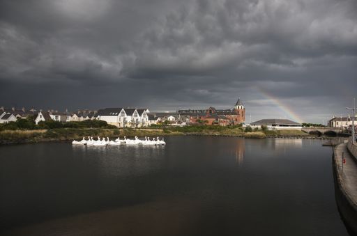 The stormy weather and a rainbow over the lake with swan boats in Newcastle, County Down