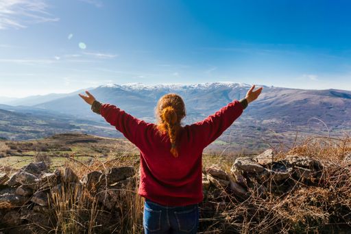 A back view of a young female hiker enjoying the beautiful view on a mountain