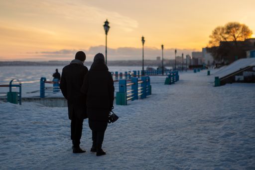 A young couple walking by a sandy beach on a cold autumn day