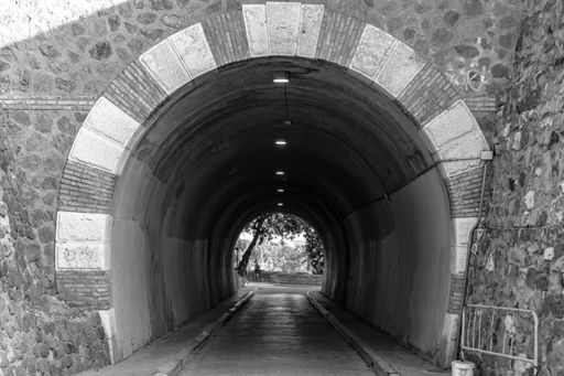 A greyscale shot of a greyscale tunnel leading to a beautiful place