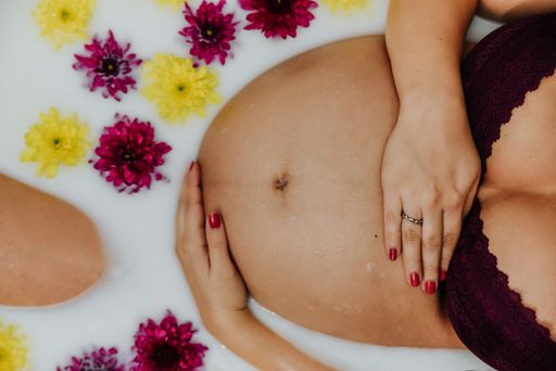 An overhead shot of a pregnant woman in a relaxing milk bath with flowers