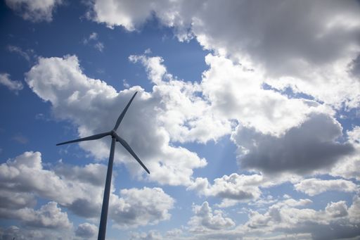 A low angle shot a windmill under the sunlight and a blue cloudy sky