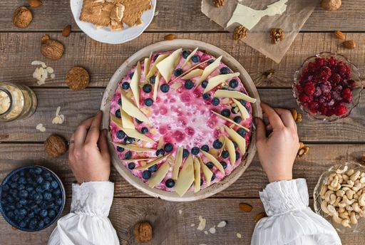 A top view of a female holding a delicious homemade cheesecake with berries