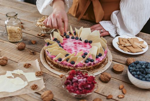 A female decorating a homemade cheesecake with berries
