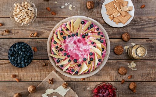 A top view of a delicious homemade cheesecake with berries on a wooden table surrounded by ingredients