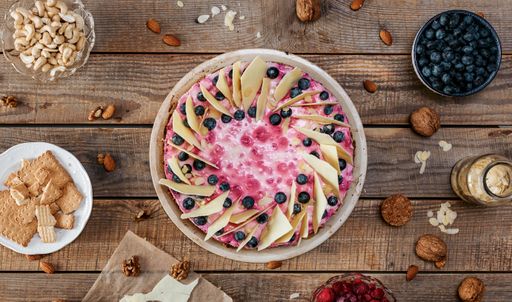 A top view of a delicious homemade cheesecake with berries on a wooden table surrounded by ingredients