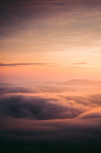 A vertical shot of clouds under an orange sunset sky