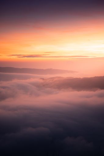 A vertical shot of clouds under an orange sunset sky