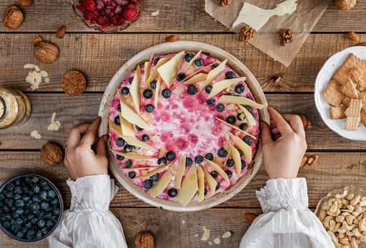 A top view o female holding a delicious homemade cheesecake with berries
