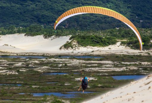 A person paragliding over a lake in the mountains