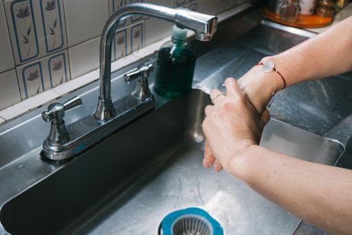 A female washing hands with soap over the sink