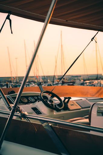 An aerial view of a sleek motorboat cruising through a peaceful harbor on a sunny day