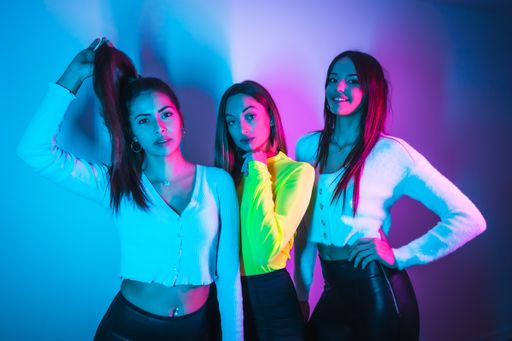 The lifestyle of young female friends partying in a disco with blue and pink neon lights