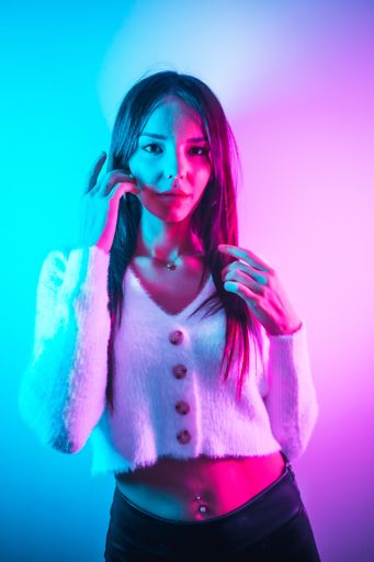 A portrait of a young brunette Caucasian girl having fun in a nightclub with pink and blue neon lights
