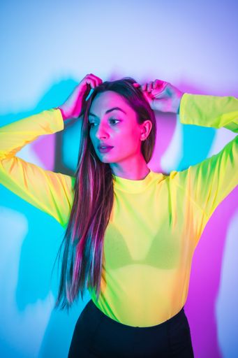 A young sexy brunette Caucasian girl in a yellow t-shirt having fun in a nightclub with pink and blue neon lights