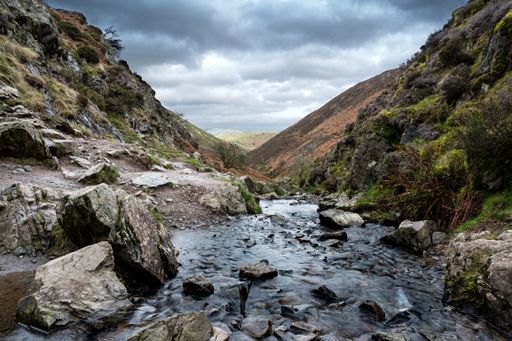 A rocky river flowing through mountains with dark clouds