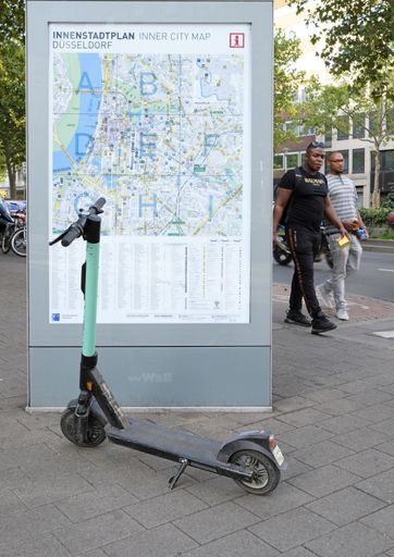 09 September 2019 - Duesseldorf, Germany : An e-scooter parked in the city center of Duesseldorf in front of a city map.