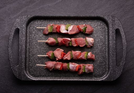 Fresh raw pieces of chicken with red and green peppers on skewers - preparation for cooking