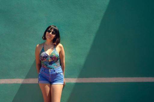 a Hispanic female from Mexico with summer clothes in front of the blue wall with a white stripe
