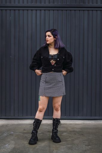 A vertical shot of a stylish European female with purple hair and tattoos