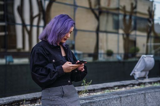 A closeup shot of a Caucasian sexy woman with purple hairs texting on the phone