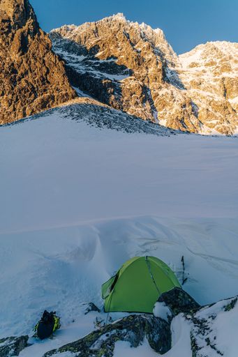 Green tent in a snowy winter mountain landscape. Extreme camping in winter aloine like conditions of High Tatras, Slovakia.