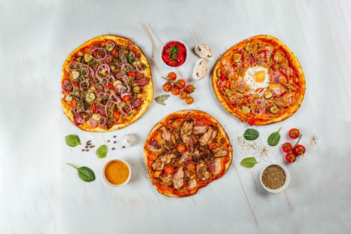 A top view of various tasty pizzas and spices
