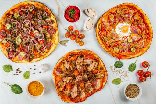 A top view of various tasty pizzas and spices