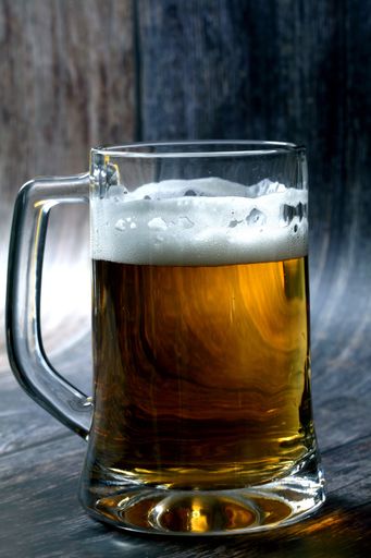 A vertical shot of a mug of beer on wooden table