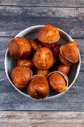 A vertical shot of a white plate with muffins on a wooden table
