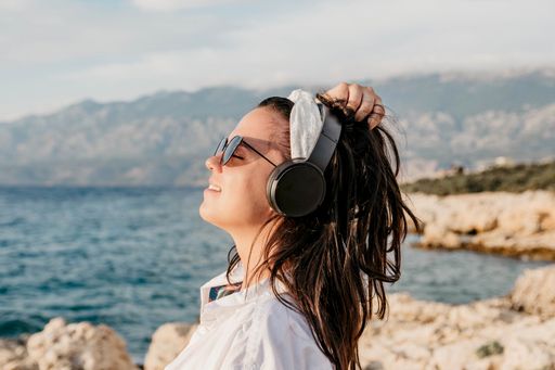 A Caucasian female with headphones on a beach in Croatia