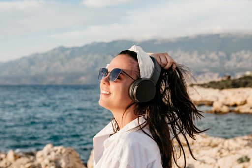 A Caucasian female with headphones on a beach in Croatia