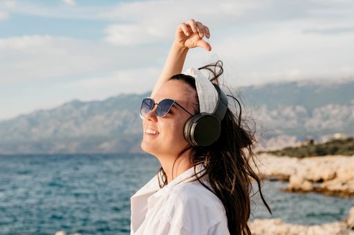 A Caucasian female with headphones on a beach in Croatia