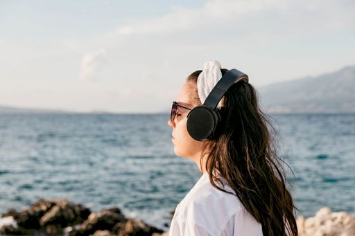 A Caucasian female with headphones on a beach in Croatia