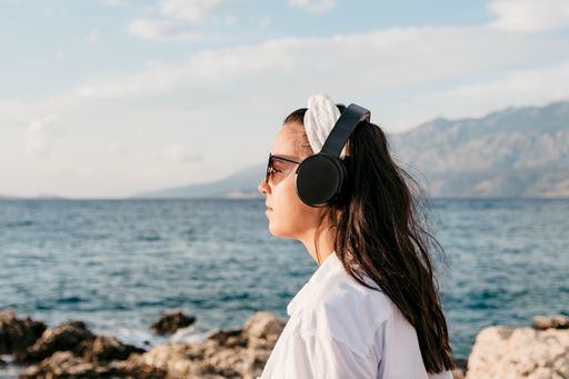 A Caucasian female with headphones on a beach in Croatia