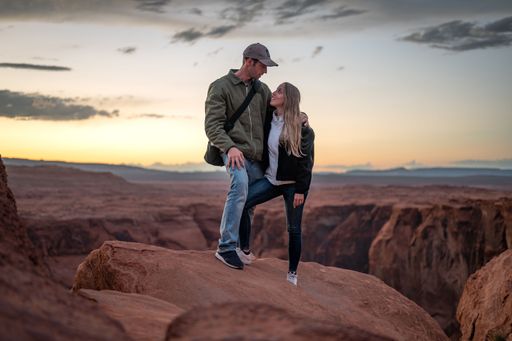 Portrait of a wedding couple looking at each other, they are standing on the rock formations of the desert at sunset