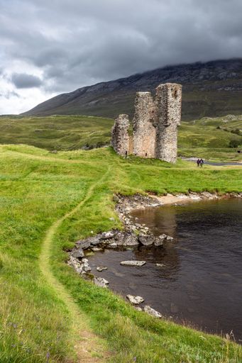 The ancient Ardvreck Castle ruin located on the edge of a tranquil lake in Scotland