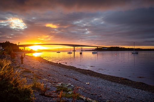 A serene sunset scene with small boats in the calm waters alongside a seaside