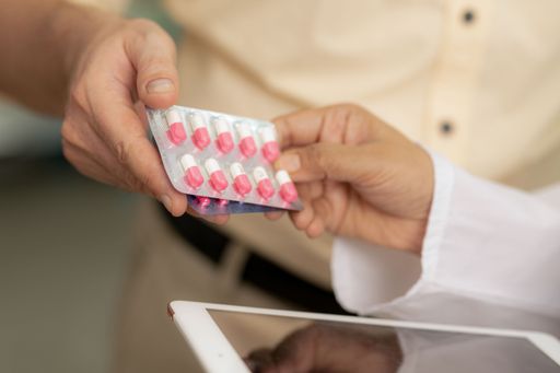 A young man receives pills from a pharmacist in a pharmacy.