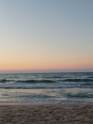 Idyllic beach scene featuring a beautiful sunset with rolling waves in the foreground