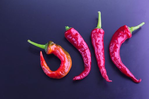 A top view of red hot chilly peppers laid out on a dark surface