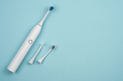 An electric toothbrush on a blue surface with its spare parts