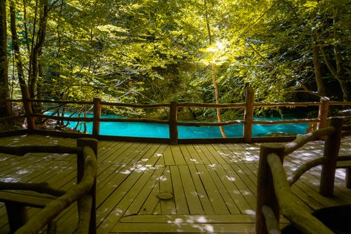 An outdoor deck area with empty chairs arranged in a row, Urederra River