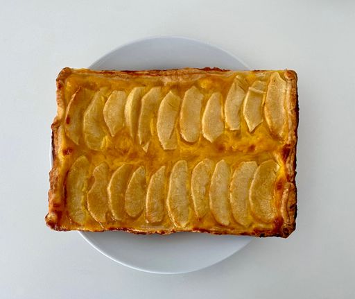 A closeup of a white plate with a freshly-baked, square-shaped apple pie.