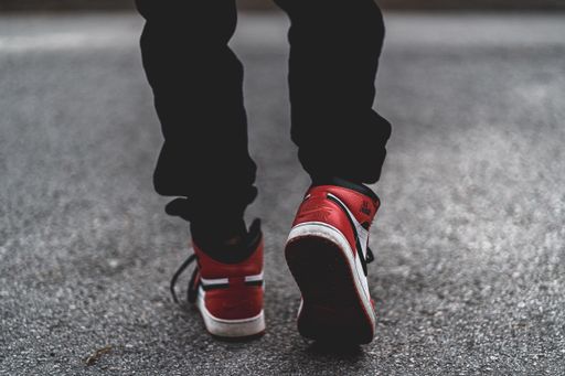 Person wearing air jordan 1s with black pants walking away on cement