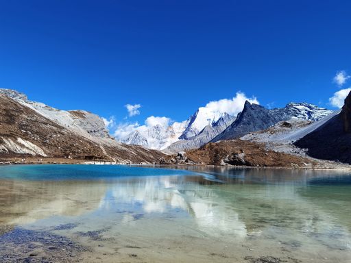 A landscape of a crystal clear lake surrounded by rocky hills under a blue sky