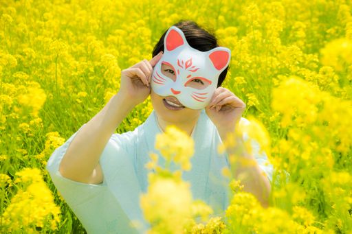 Japanese woman wearing a cat mask enjoys the Spring season in beautiful Yellow Flowers or Nanohana Blooming in Japan.