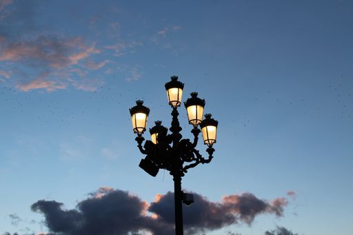 A low angle view of a street lamp under a cloudy sky during the sunset in the evening